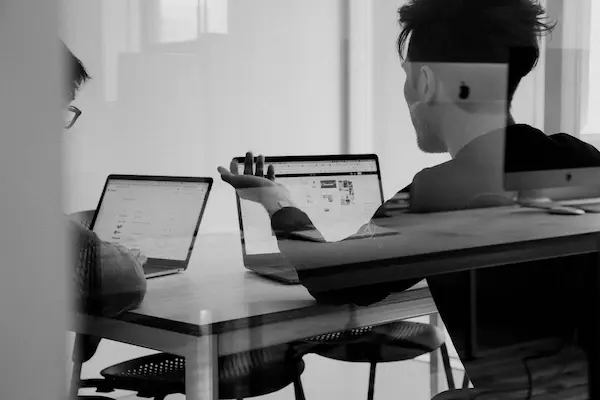 Two journalists working together at a desk with laptops